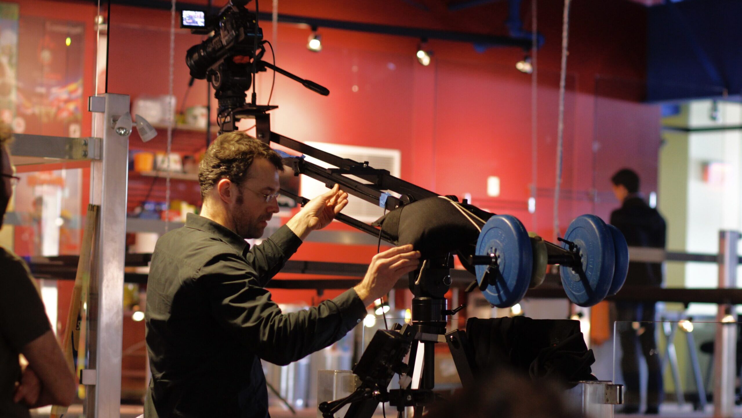 cameraman works with camera on mini jib crane, counterbalanced with weights, interior scene